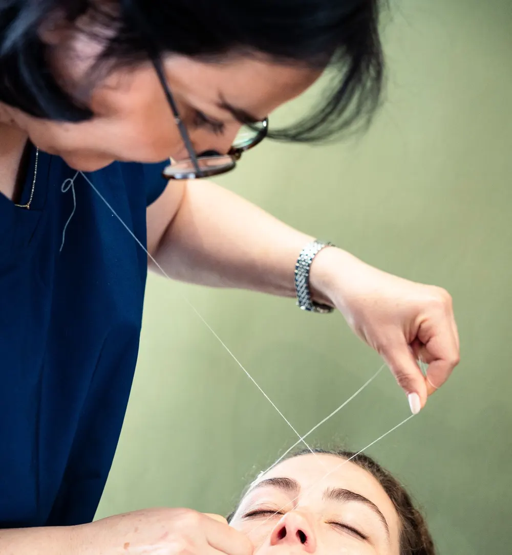 Eyebrow threading in progress at Skin and Beauty Box Bristol, cotton thread lifting hairs in a line